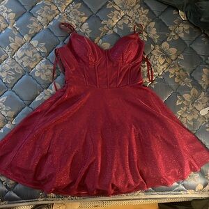 A pink glittery homecoming or prom dress with a flower back and a corset top.